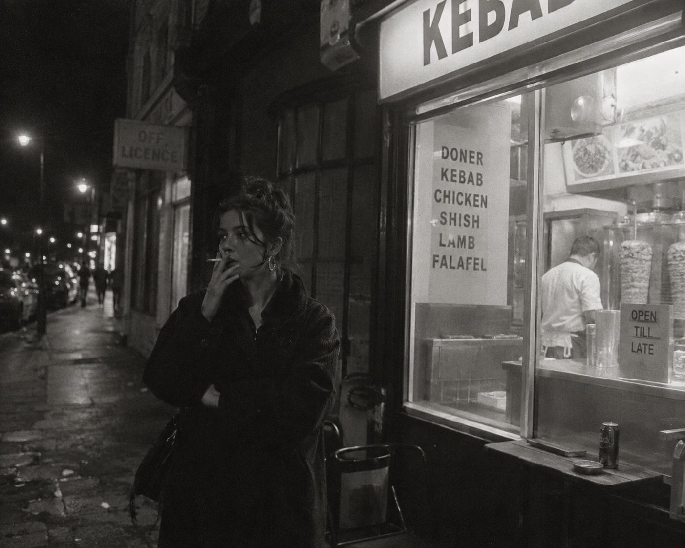 A woman smoking outside a kebab shop at night