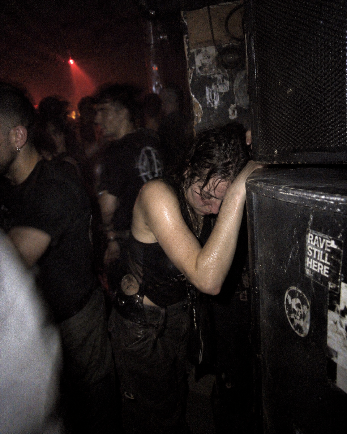 Exhausted clubgoer leaning against a speaker stack