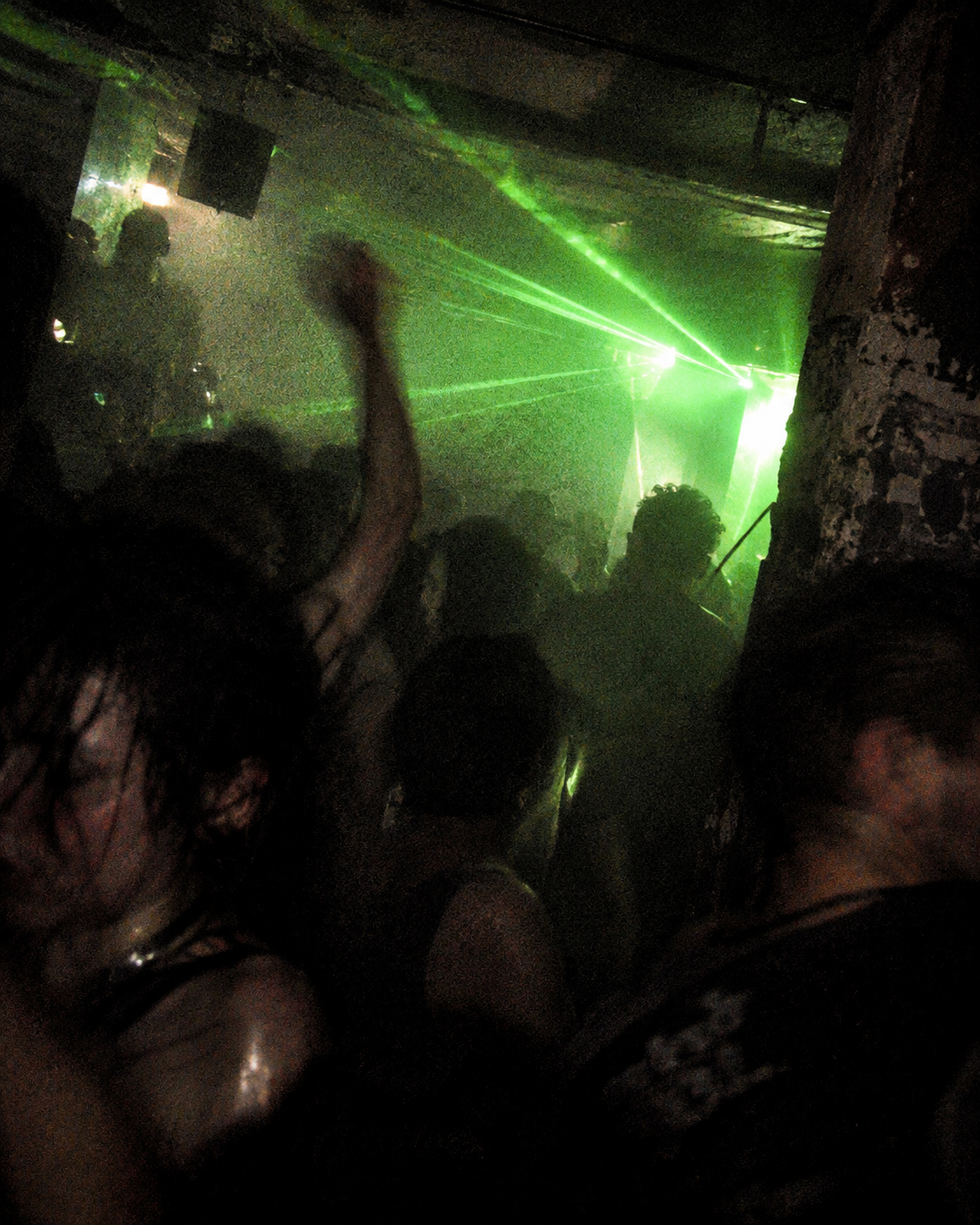 Rave crowd silhouetted beneath green laser light