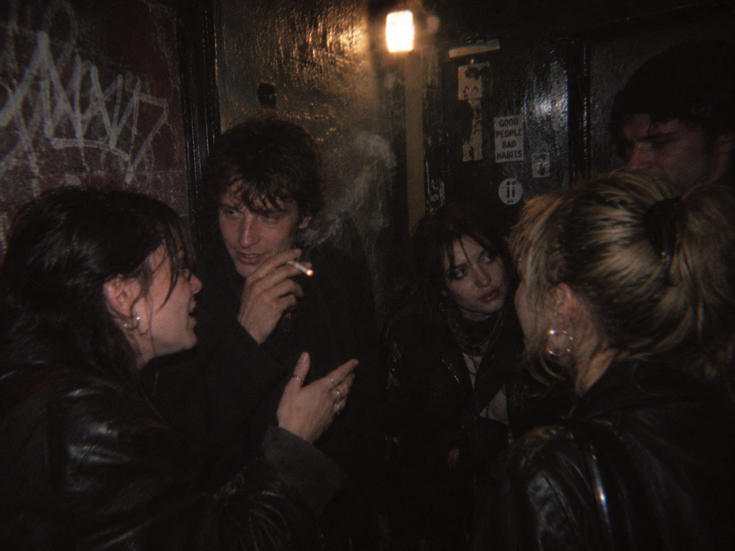 Group talking and smoking in a dark club corridor