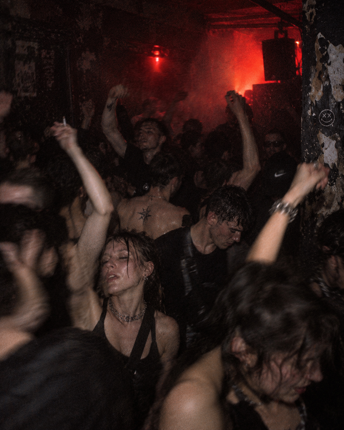 Sweaty crowd dancing in a dark red-lit club