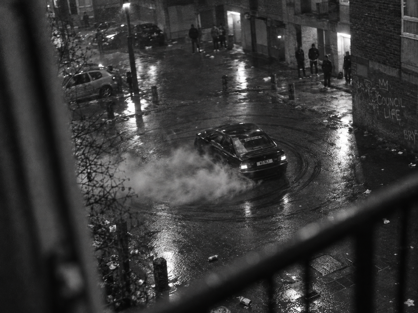 BMW doing donuts in a rain-slicked estate courtyard