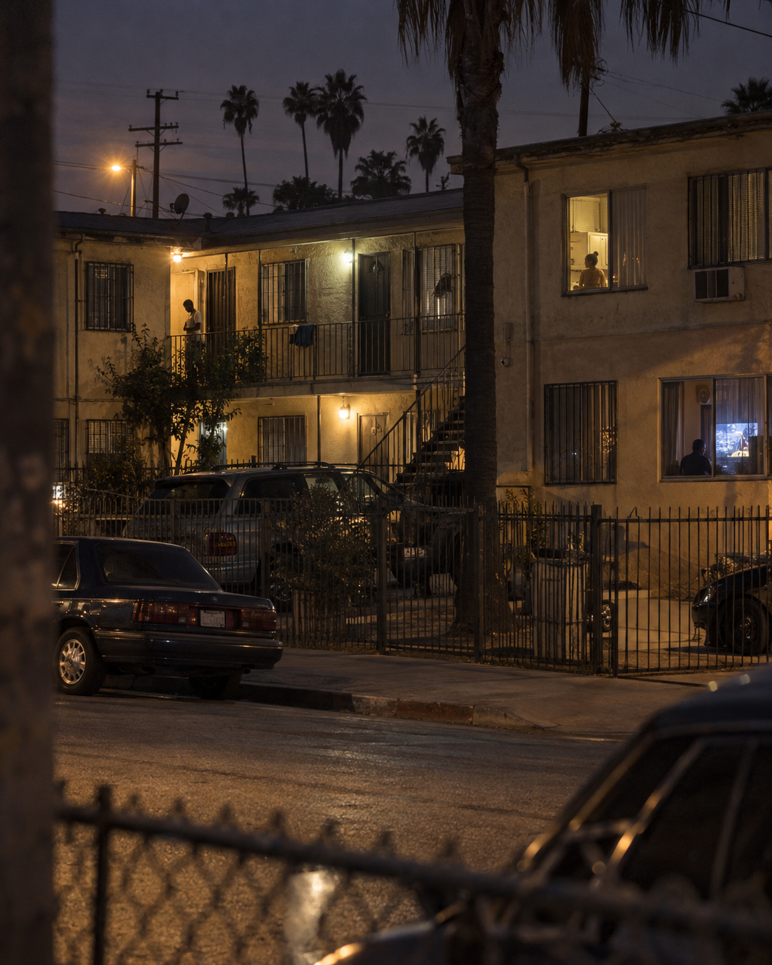 Los Angeles apartment building at dusk with isolated figures visible through windows