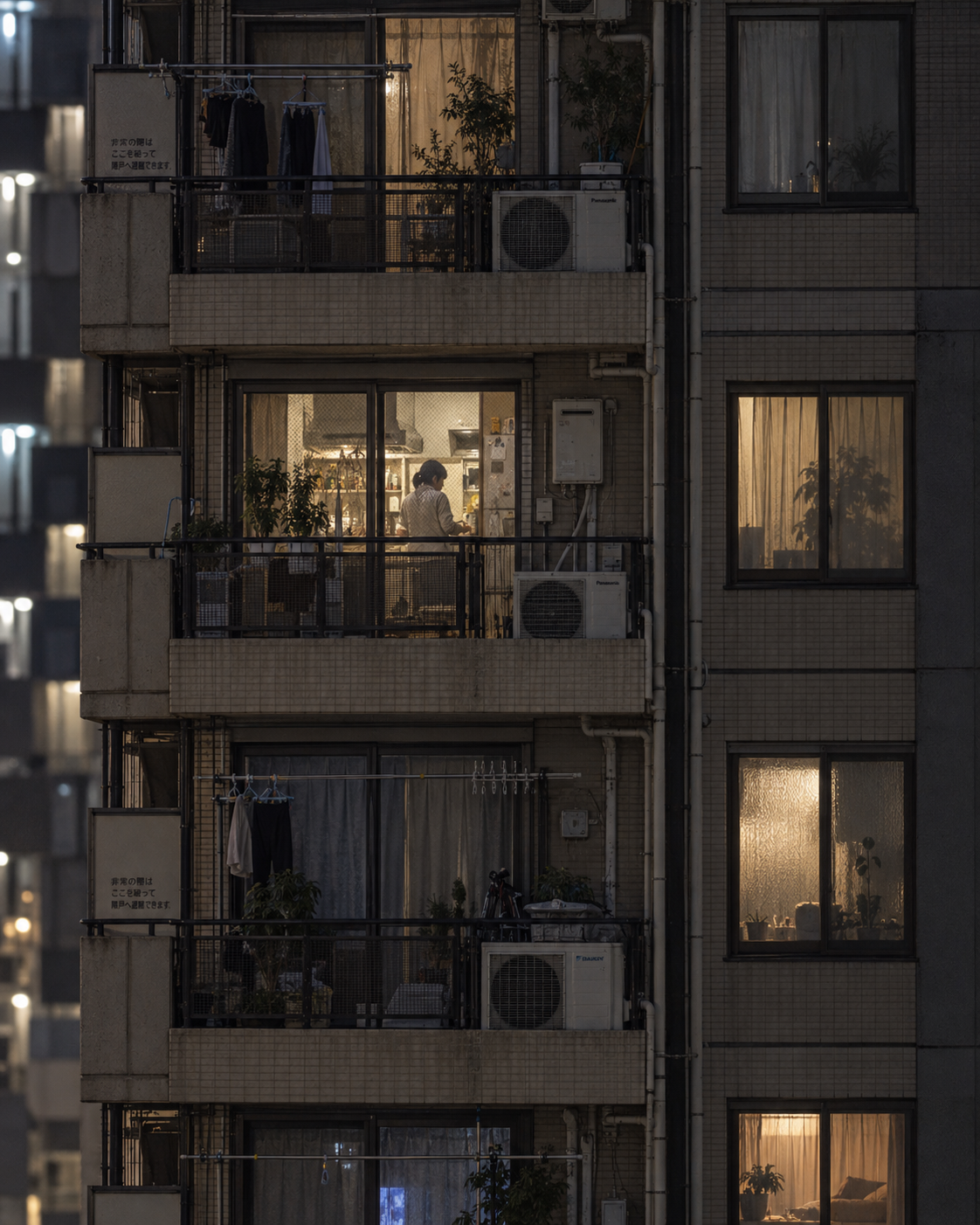 Japanese apartment facade with balconies and a single resident working inside